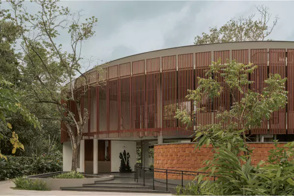 Curved timber-clad building of the Ayurveda campus with gardens