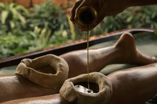 Therapist pouring medicated oil during an Ayurvedic treatment