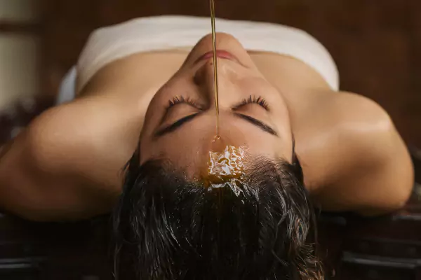 Shirodhara therapy: warm herbal oil poured onto the forehead