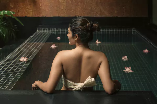 Guest relaxing in the flower-strewn pool at Nirava
